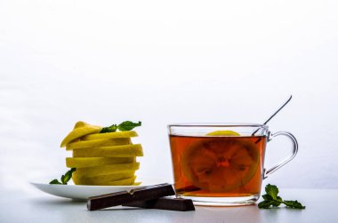 Cam bardak çay, nane, çikolata ve beyaz zemin üzerine kesilmiş limon ile