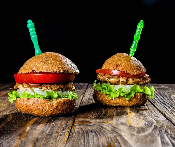Hamburger tavuk pirzola ananas, salata ve domates, siyah bir zemin üzerine ahşap bir masa üzerinde