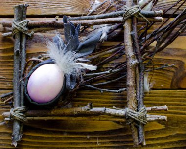 Bir çerçeve içinde renkli bir yumurta Paskalya bileşimi twigs ahşap arka plan üzerinde bir yuva