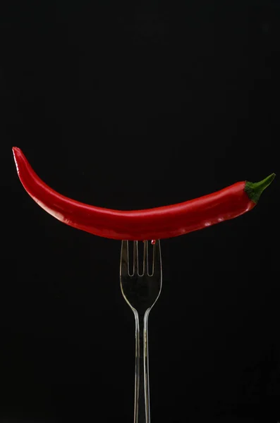 Tenedor con gran pimiento rojo y perejil sobre un fondo negro —  Fotos de Stock