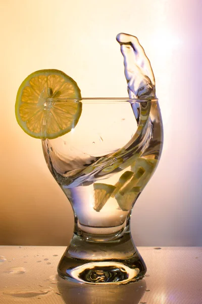 Splash of water in a glass with lemon in beige tones — Stock Photo, Image