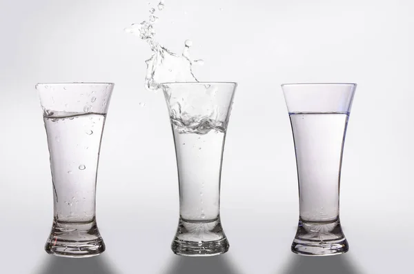 Üç bardak ve bir sıçrama arka planı gri su