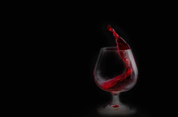 Подрібнення червоного вина в келиху на чорному тлі — стокове фото