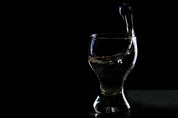 Выплеск воды в стакане на чёрном фоне — стоковое фото