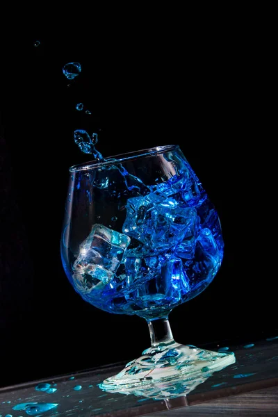 Splash of water in a glass with ice on a black background — стоковое фото