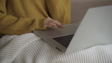 Öğrenci evdeki kanepede battaniyenin altında dizüstü bilgisayar kullanarak online danışmanlık yapıyor. İnsanlar ve aygıtlar kavramı.