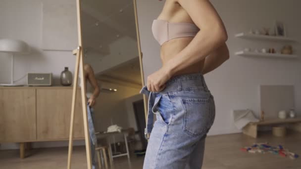 Vacker ung sportig kvinna tittar på sina magmuskler. Vacker ung sportig flicka tittar på hennes abs i jeans — Stockvideo