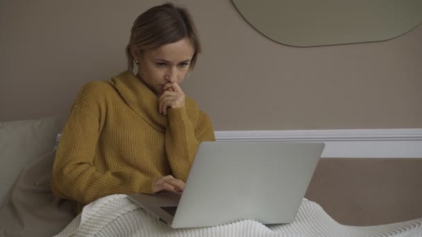 Studente che utilizza computer portatile a casa sdraiato sul divano sotto coperta utilizzando serching computer per la consultazione online. Concetto di persone e dispositivi . — Video Stock