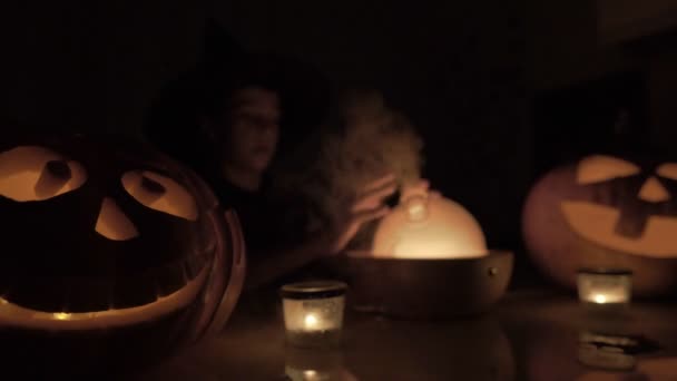 Devítiletý chlapec si na Halloween hraje na čaroděje. S kouzelnou lampou a dýní na stole v noci. — Stock video