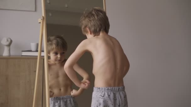 Χαριτωμένο καυκάσιο αγόρι δείχνει μυς στο μπροστινό καθρέφτη, αθλητική δύναμη, υγειονομική περίθαλψη. — Αρχείο Βίντεο