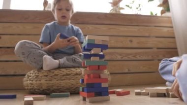 İki erkek kardeş yere tahta bloklardan bir kule inşa ediyorlar.