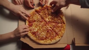 İnsan elleri açık kutudan sıcak İtalyan pizzasından dilimler alıyor, parti yemek servisi konseptinde, arkadaşlar birlikte yemek yerken eğleniyor, manzarayı kapatıyorlar..
