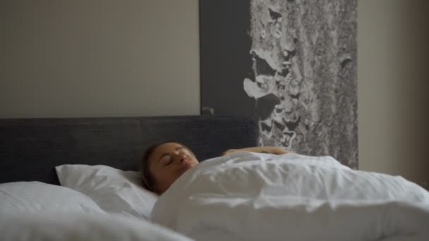 Frau wacht am Morgen auf und nimmt Smartphone auf einmal. Frau wacht morgens im Bett auf und nimmt Smartphone gleich mit. — Stockvideo