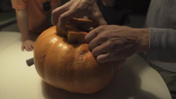 Feliz Dia das Bruxas. Pai e filhos a esculpir abóbora na mesa em casa. Família se preparando para férias. Vista superior. Fechar — Vídeo de Stock