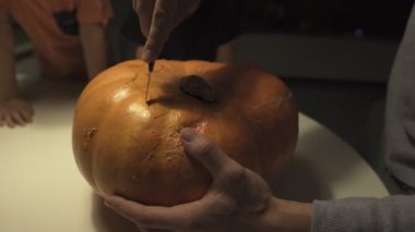 Cadılar bayramın kutlu olsun. Baba ve oğulları evdeki masaya balkabağı oyuyorlar. Aile tatili için hazırlanıyor. Üst Manzara. Kapat.