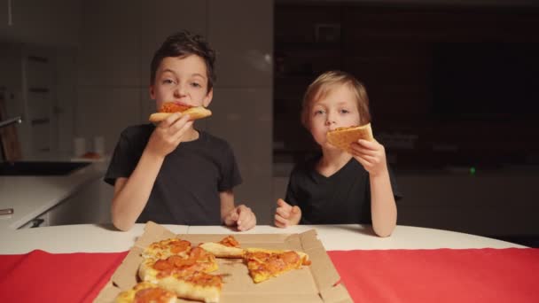 두 소년 이 심야에 집 부엌에서 피자를 먹고 있습니다. 혼자 서 집에 있는 소년들. — 비디오