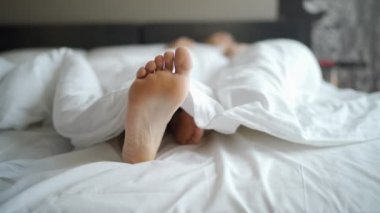 Kadın ayakları üzerinde yatağın altına beyaz battaniye. Uyku ve kavram rahatla. Tatil ve tatil Tema.