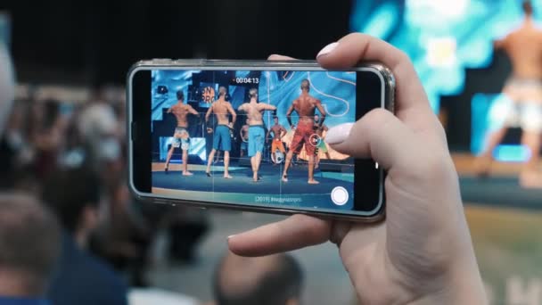 俄罗斯莫斯科- 2019年11月：在体育和医疗博览会论坛上有人用智能手机射击男子体格竞赛 — 图库视频影像