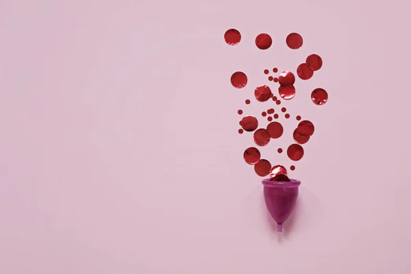 Menstrual Κύπελλο με κόκκινα σωματίδια σε ροζ φόντο, έννοια της υγείας των γυναικών και της οικολογίας του πλανήτη — Φωτογραφία Αρχείου