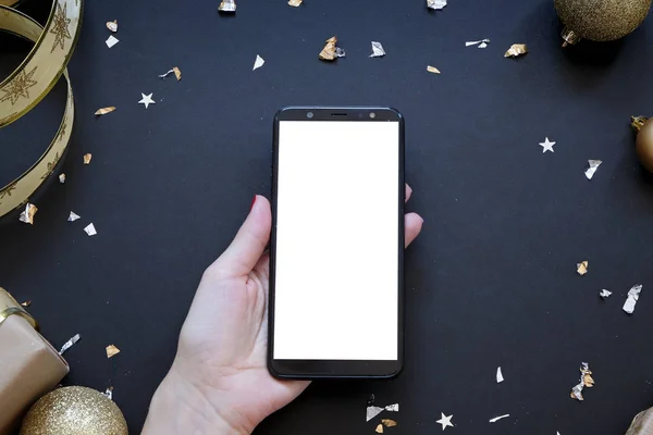 Noel kompozisyonunun ortasında siyah ve altın renginde akıllı bir telefon.