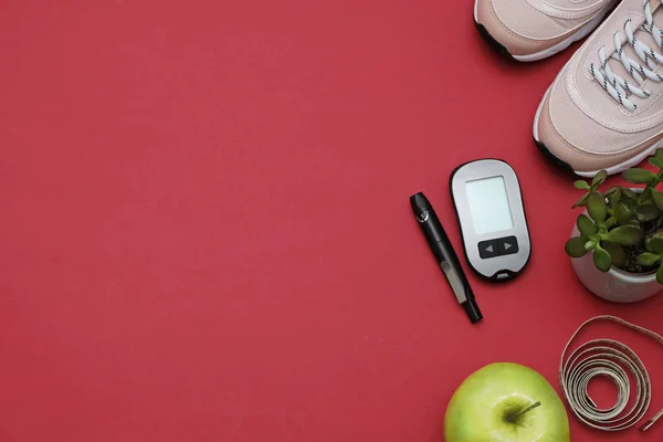 Composition with diet diabetes weight loss concept - Sneakers, tape measure, glucometer on a red background, space for text