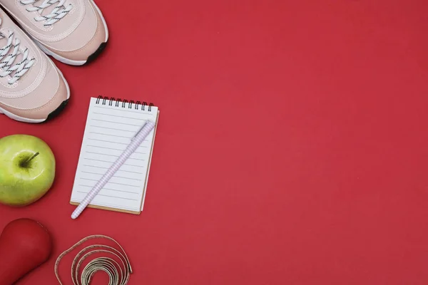 Flat lay with diet weight loss concept - Sneakers, tape measure, glucometer on a red background, space for text