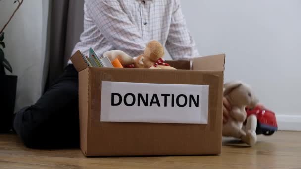 Женщина-волонтер кладет игрушки для детей в ящик для пожертвований, пожертвований и благотворительности — стоковое видео