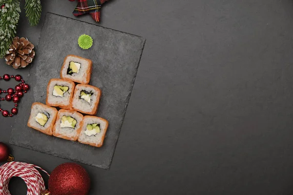 Sushi for christmas concept. Edible christmas tree made from Philadelphia roll on black background.