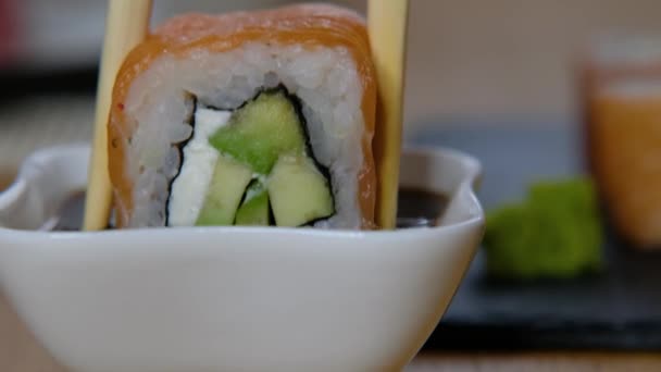 Bezorging food concept: iemand dompelt Philadelphia rollen sushi in sojasaus, close-up — Stockvideo