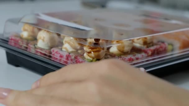 Concepto de comida de entrega: mujer apertura caja de plástico con rollos de sushi — Vídeos de Stock