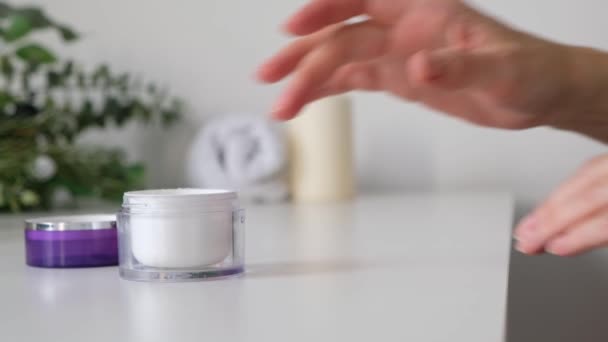 Vrouw die crème op haar handen, witte achtergrond, close-up. Kuuroord cosmetica — Stockvideo