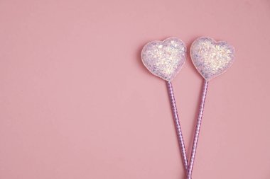 Sevgililer Günü kompozisyonu pembe arka planda iki parıltılı kalp, düz uzanmış