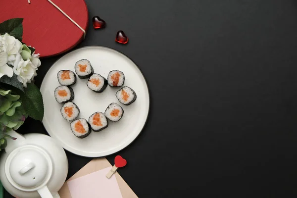 Sevgililer Günü için suşi - kalp şeklinde yuvarlan, siyah arka planda tabak üzerinde. Düz yatıyordu.