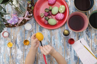 Paskalya yumurtalarını yumurta boyasıyla boyayan çocukların ellerini kapatın. Yukarıdan görüntüle