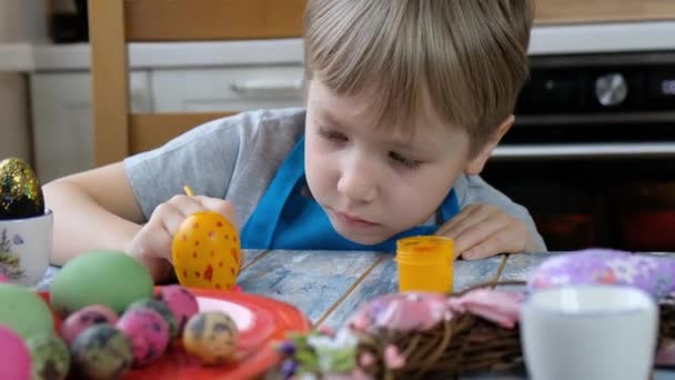 Niño niño de cinco años para colorear huevos de Pascua en la cocina . — Vídeo de stock