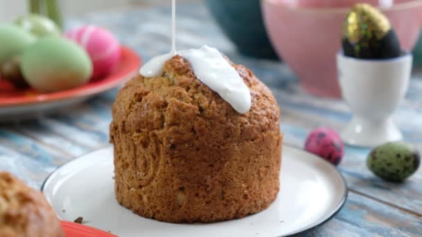 Somebody putting white glaze on the easter cake, on the table with colorful eggs — Stock Video