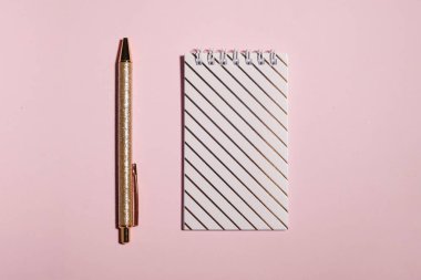 Pembe arka planda modern not defteri ve kalem, üst görünüm