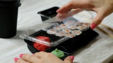 Plastik kutuyu rulo suşiyle açan kadın, kapat. Teslimat gıda konsepti.