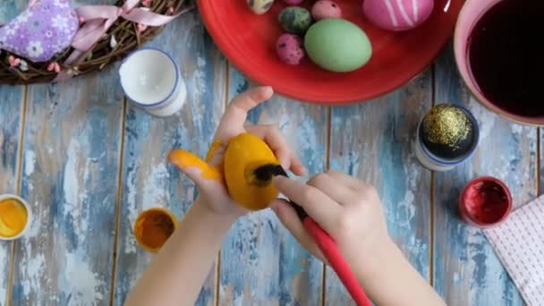 Sluiten van jonge handen kleuren paaseieren met eierkleurstof. Uitzicht van bovenaf — Stockvideo
