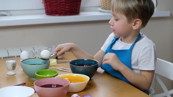 Pět let chlapec dítě zbarvení velikonoční vejce s vaječným barvivem. — Stock video