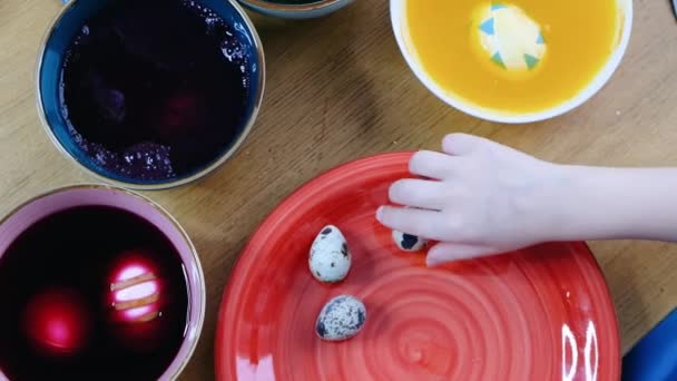 Κοντινό πλάνο του παιδιού χέρια χρωματισμός πασχαλινά αυγά με βαφή αυγών. Άποψη από ψηλά — Αρχείο Βίντεο