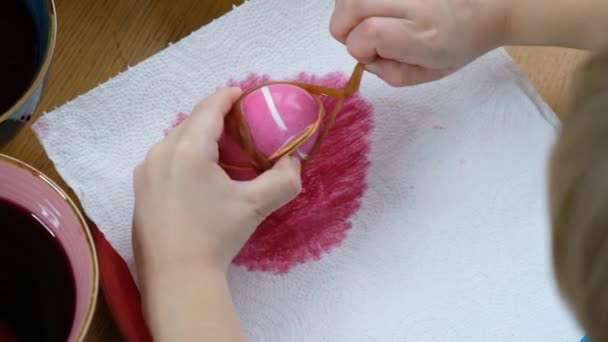 用彩蛋染料给复活节彩蛋上色的小孩手的特写. — 图库视频影像