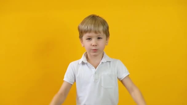 Primer plano del chico rubio cruzando brazos y mostrando parada, tabú, prohibición sobre fondo amarillo — Vídeo de stock