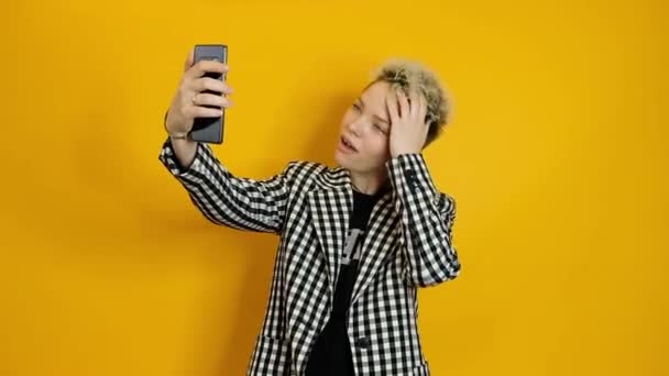 Lachende vrolijke stijlvolle vrouw maken selfie op smartphone over gele achtergrond — Stockvideo