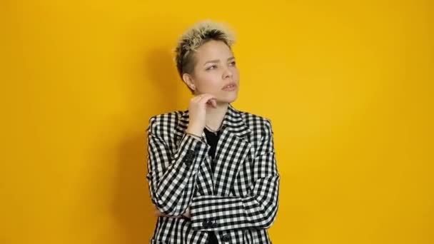 Stylish woman thinking and having an idea isolated over yellow background — 图库视频影像