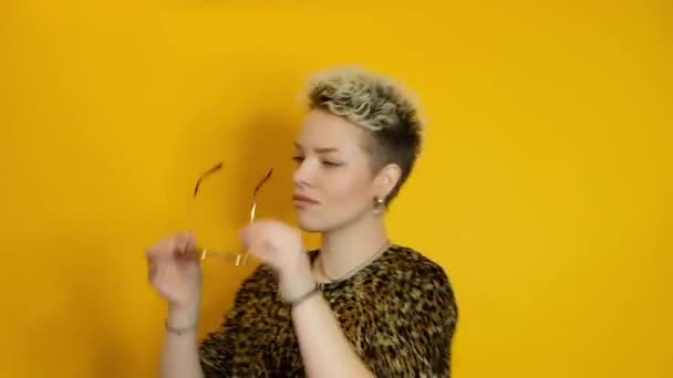 Gelukkig zorgeloos stijlvolle vrouw in bril dansen over gele achtergrond — Stockvideo
