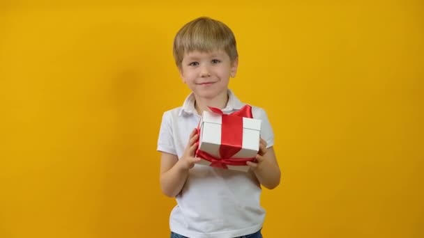 Αστεία χαρούμενο μικρό παιδί χαμογελά με δώρα σε κίτρινο φόντο — Αρχείο Βίντεο