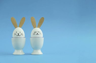 Mavi Paskalya arka planında fotokopi alanı var. Tavşan gibi süslenmiş iki beyaz yumurta. Tebrik kartı