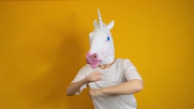 Tuhaf komik bir video. Tek boynuzlu at kafalı kadın sarı arka planda dans ediyor.