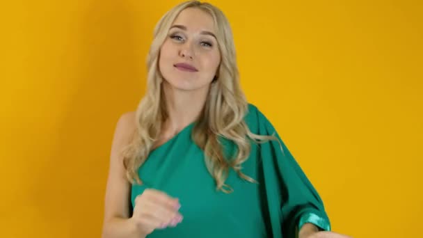 Красива щаслива блондинка танцює ізольовано на жовтому фоні — стокове відео
